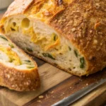 Freshly baked jalapeno cheddar sourdough bread, sliced to show cheesy, spicy interior on a cutting board.