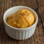A single scoop of creamy homemade healthy pumpkin ice cream in a white bowl, spiced and ready to enjoy.