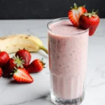 Creamy strawberry yogurt smoothie in a glass with fresh strawberry garnish.