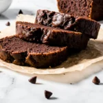 Sliced chocolate and zucchini bread on a cutting board, ready to serve. Rich, moist chocolatey quick bread.