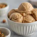 Multiple creamy scoops of homemade peanut butter ice cream in a white bowl, perfect from our delicious recipe.