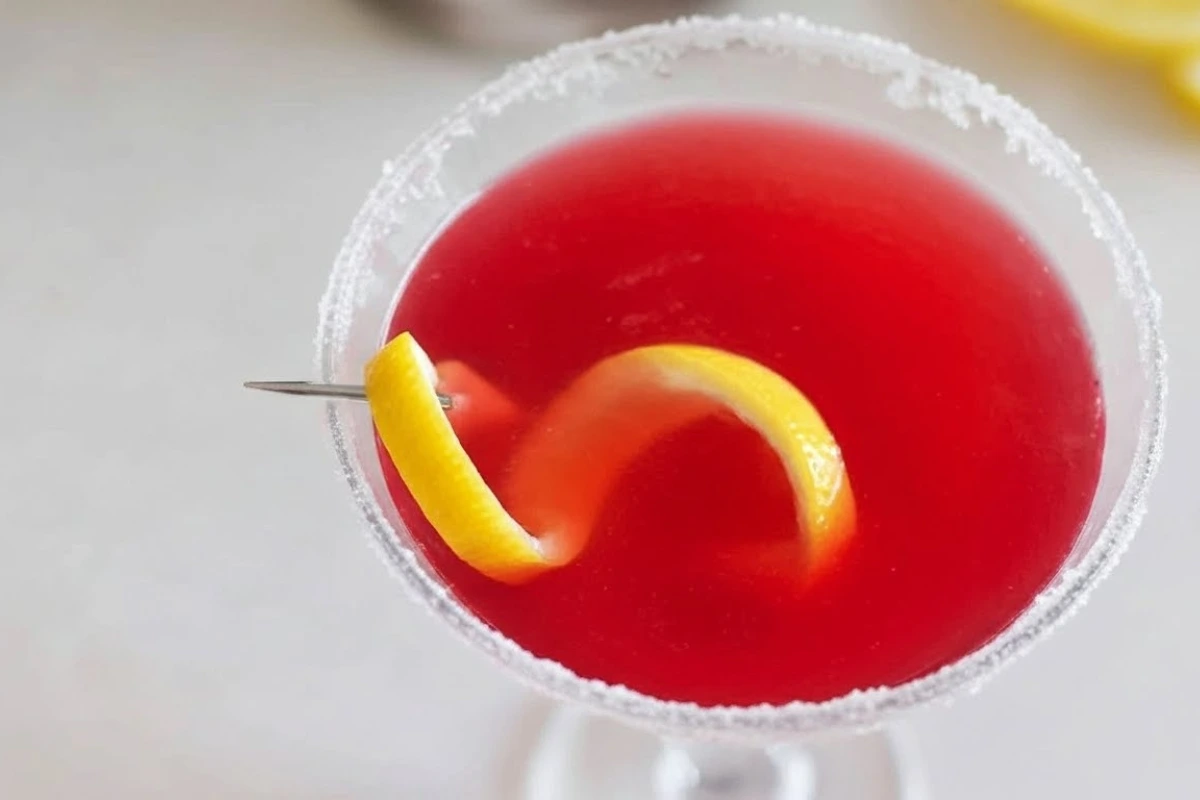 Top-down view of a vibrant cranberry lemon drop cocktail with a lemon twist and sugared rim.