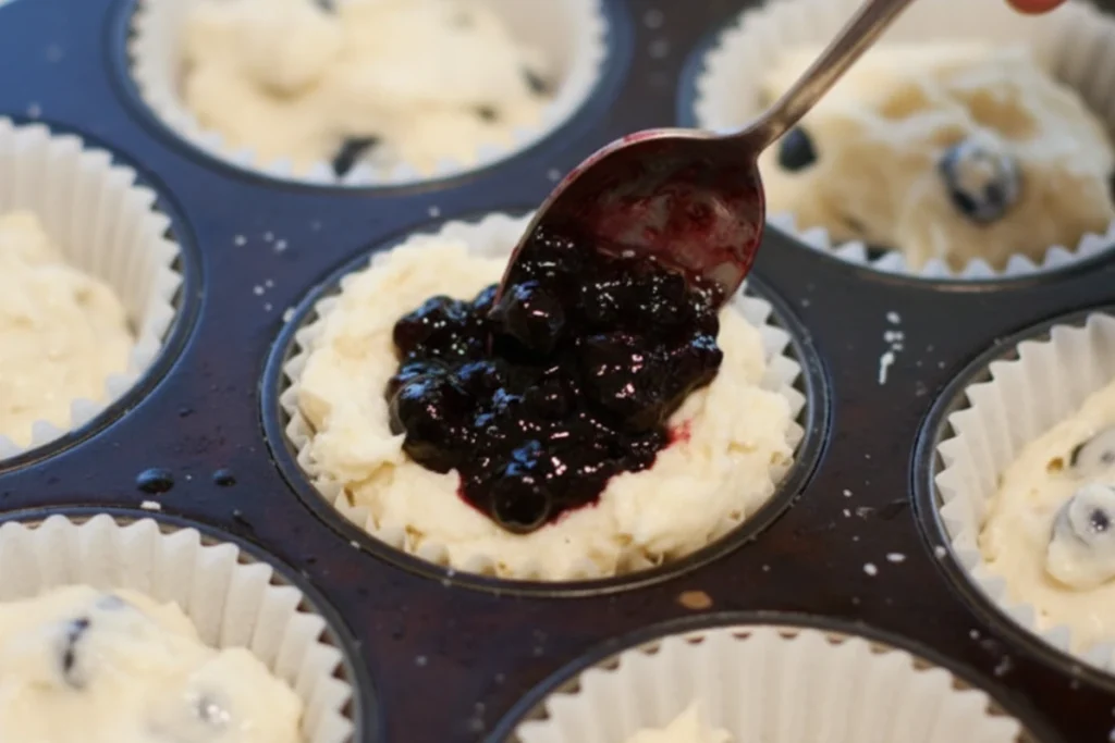 Adding blueberry preserves to muffin batter for a double blueberry muffins recipe.